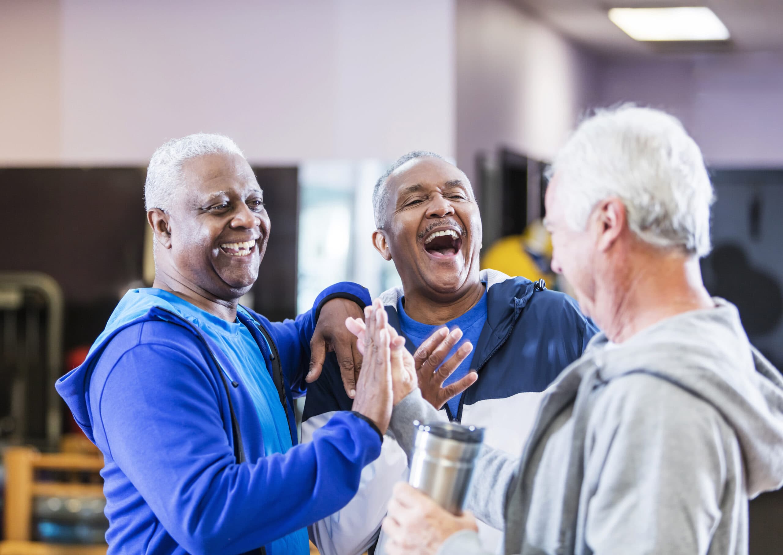 Three men hanging out at gym, talking and laughing.